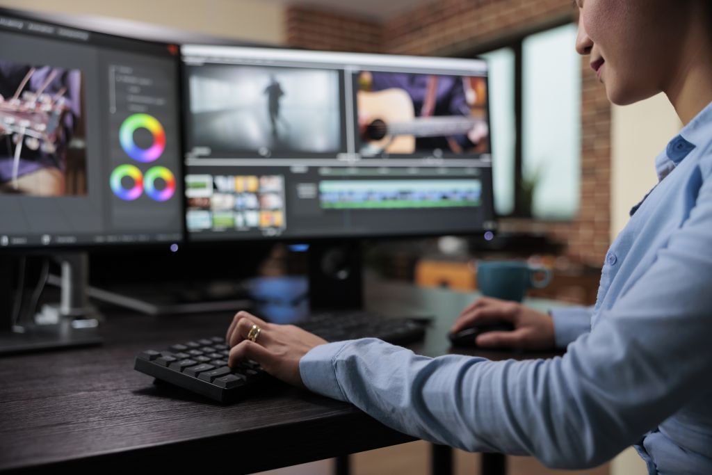 Close up shot of professional videographer sitting at desk while enhancing movie footage using specialized software.
